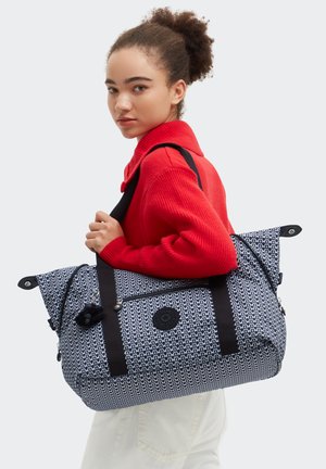 Borsa a tracolla blu navy con motivo a fantasia, dettagli neri, tasca con cerniera e logo tondo, realizzata in tessuto strutturato, portata a spalla.