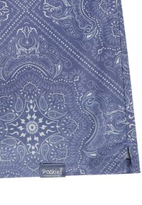 Mėlynas audinys su sudėtingu baltu paisley raštu, kuriame yra detalių sukimų ir taškų. Apačioje etiketė su užrašu "Pockies Couch Culture".