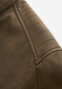 Bruine leren jas mouw met gewatteerde gestikte details en naadlijnen op een witte achtergrond.