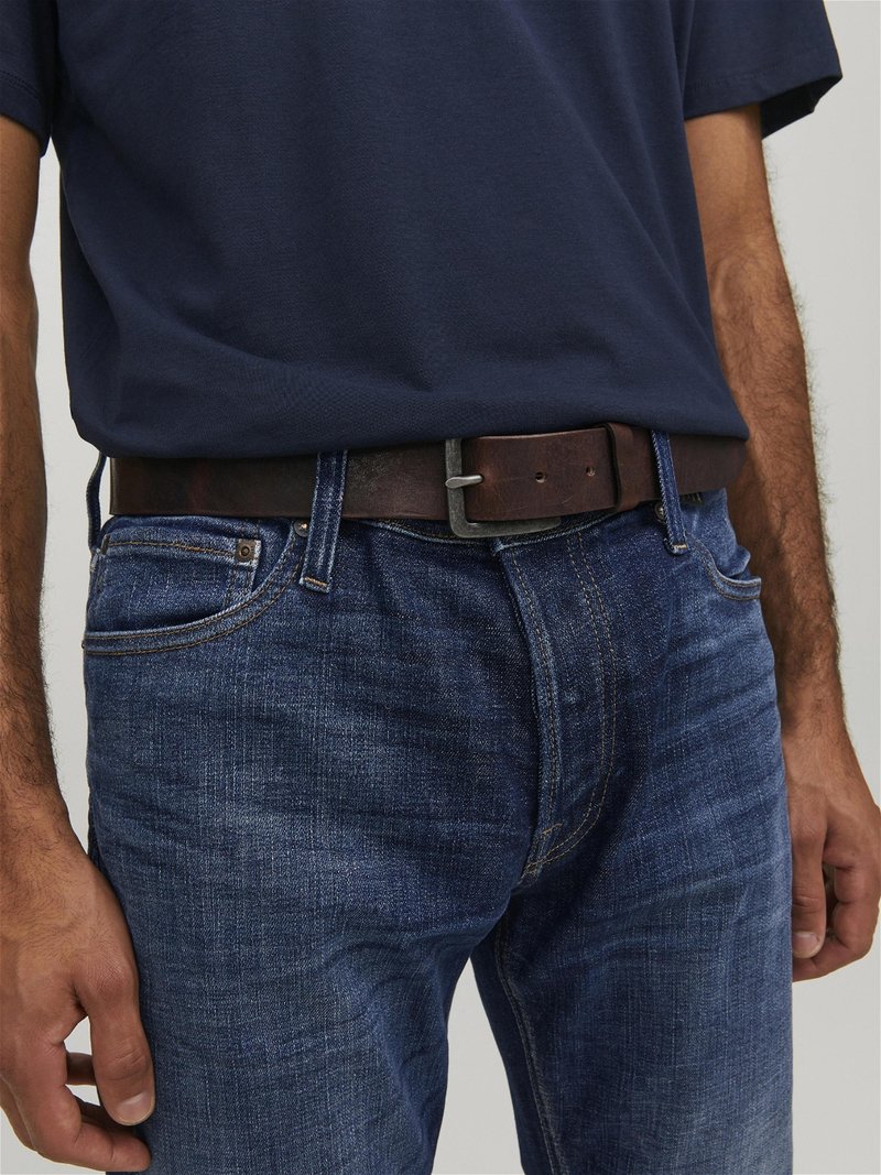 Mørkeblå t-shirt kombineret med blå denim jeans. En brun læderbælte har en simpel metalspænde. Teksturen viser let falmede detaljer.