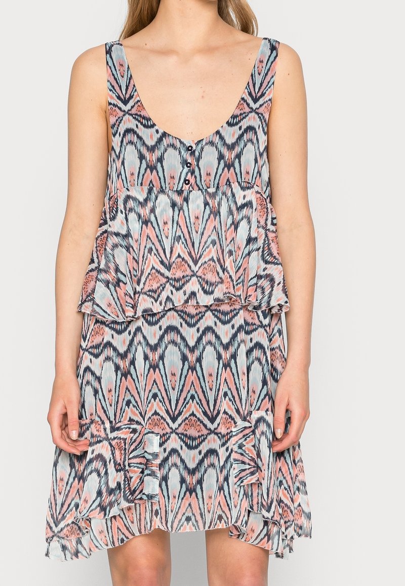 Robe sans manches avec un décolleté en V, présentant un motif abstrait rose et bleu, des volants superposés et des détails de boutons à l'avant. Tissu léger.