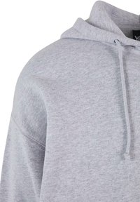 Grå sweatshirt med hætte, der har en blød tekstur, justerbare snore og en afslappet pasform. Søm detaljer synlige på skulderen.
