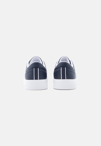 Ζευγάρι ναυτικό μπλε αθλητικά παπούτσια με λευκές σόλες, εμφανιζόμενα από πίσω, πάνω σε απλό λευκό φόντο.