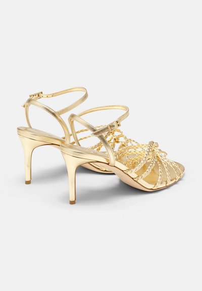 Goldene Sandalen mit geflochtenen Riemen, offenen Zehen und Knöchelverschluss. Glänzende Textur und schlanker Stiletto-Absatz.
