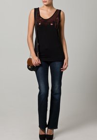 Black sleeveless top with sequin embellishments, paired with dark blue jeans and black heels. Crossbody bag with tan and black accents.