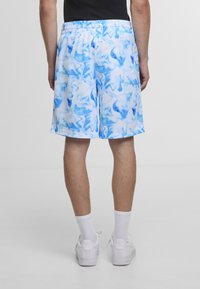 Blå og hvite marmorerte badebukser med elastisk midjebånd, knelang lengde, glatt tekstur og lett syntetisk materiale.