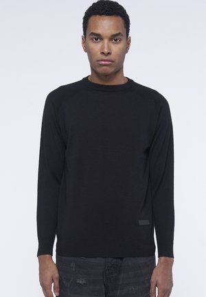 Maglione nero a maniche lunghe con colletto a girocollo, tessuto testurizzato e orlo a coste. Presenta una toppa con logo sul lato sinistro.
