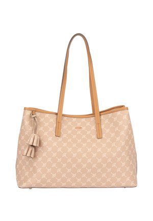 Sac cabas beige avec motif clair, deux longues poignées couleur sable et trois décorations à pompons suspendues d’un côté.