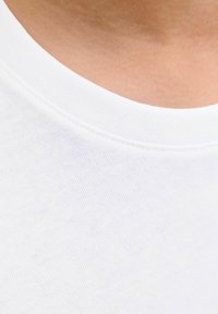 Witte katoenen t-shirtstof met een gladde textuur, voorzien van een ronde halslijn en subtiele stikdetails. Close-up van het kraaggebied.