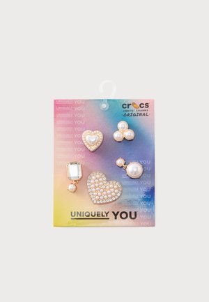 Cinco charms Crocs Jibbitz con temática de perlas que presentan corazones, racimos y una gema rectangular en una colorida tarjeta "Uniquely You".