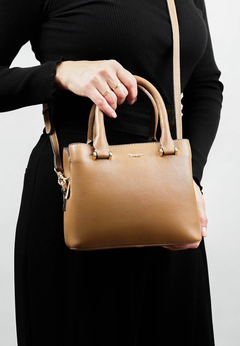Bruine leren handtas met dubbele handvatten aan de bovenkant en een afneembare schouderriem. Beschikt over gouden hardware en een gestructureerde afwerking.