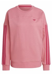 Rosa sweatshirt med långa ärmar. Ribbad halsringning och muddar. Har tre mörkare rosa ränder längs ärmarna och en liten logotyp på bröstet.