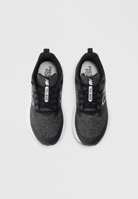 Baskets de sport noires avec un dessus en tricot texturé, des accents blancs contrastants et une semelle rembourrée. Comprend des lacets et une languette.