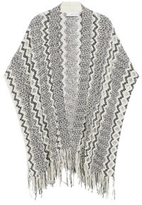 Poncho tricoté noir et blanc avec motifs en zigzag et textures, ouverture à l'avant et bordure à franges.
