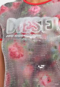 Vrchný diel z priesvitnej striebornej sieťoviny s kvetinovým vzorom, okrúhlymi flitrami a červeným lemovaním. Na prednej strane je veľké logo v reflexnom potlači.