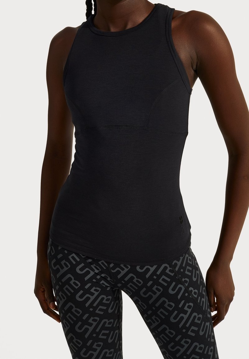 Černý bezrukávový sportovní top s přiléhavým střihem, s kulatým výstřihem a jemnými švy, spárovaný s vzorovanými černými legínami.