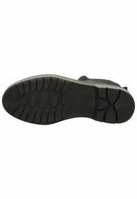 Suela de goma negra con agarres texturizados, que presenta patrones ovalados y circulares. Diseño robusto con una ligera curvatura en el talón.