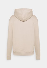 Sweat à capuche beige avec manches longues, poignets et ourlet côtelés, présenté de dos sur un fond clair uni.