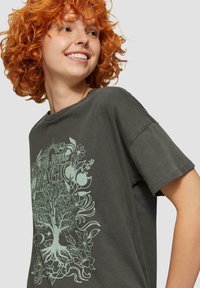 Donkergrijs T-shirt met korte mouwen, voorzien van een lichtgroene bloemen- en boomgrafiek op de voorkant. Relaxte pasvorm met een ronde hals.