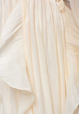 Tissu crème doux et fluide avec de légers plis et un éclat délicat, créant des plis élégants en couches et une texture subtile.