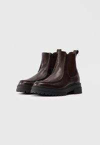 Bruine leren Chelsea-boots met elastische zijpanelen, textuur rubberen zolen en lusjes voor eenvoudig aan- en uittrekken. Robuuste zool voor stabiliteit.