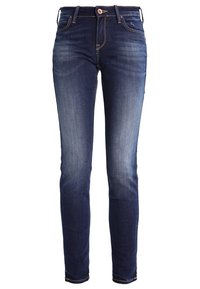 Jeans ajustados de color azul oscuro con un frente desgastado, costuras claras, diseño de cinco bolsillos y un cierre de botón que presenta un pequeño detalle de logo.