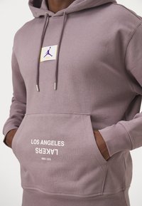 Felpa lavanda realizzata in tessuto morbido, con tasca a marsupio frontale, cappuccio regolabile con cordino e logo stampato "LOS ANGELES LAKERS" in bianco.