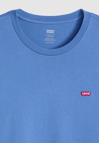 Fénykék pamut póló. Kerek nyakkivágással és egy kis piros Levi's logós folttal a bal mellen. Simaság, egységes textúra.
