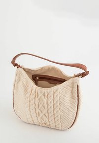 Bolso de tela de punto color crema con un diseño texturizado de cable, correa de cuero marrón y un bolsillo interior con cremallera. Forro suave y marca sutil.