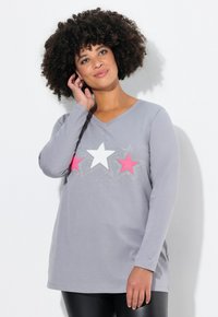 Grijs T-shirt met lange mouwen, voorzien van een V-hals, drie sterren in roze/wit en kristalaccenten langs het ontwerp. Zachte stofstructuur.