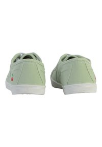 Scarpe slip-on in tela verde con suole in gomma bianca e cuciture. Caratterizzate da un piccolo ricamo di ciliegia sul lato e un colletto imbottito morbido.