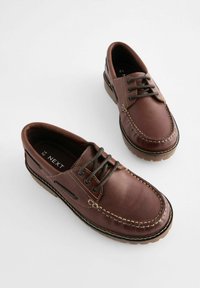 Braune Leder Schnürschuhe mit Nahtdetails, Gummisohlen und metalischen Ösen. Rundkopfdichtung im klassischen Bootsschuhstil.