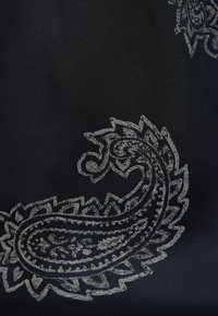 Czarna tkanina z detalicznym białym wzorem paisley, zawierającym skomplikowane linie i zawijasy, różniące się rozmiarem i orientacją na całej powierzchni.