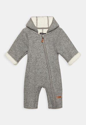 Combinaison bébé en polaire grise avec capuche, fermeture éclair diagonale à l'avant et doublure en polaire blanche visible aux poignets et à l’intérieur de la capuche.