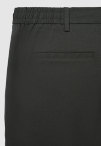 Schwarze Stretchhose mit elastischem Bund, glatter Textur und kleinem Gesäßtaschen mit sauber verarbeitetem Saum.