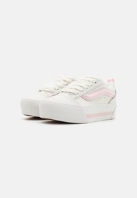 Witte canvas sneakers met lichtroze accenten, ronde neus, platte rubberen zool en textuurdetails op de zijkanten en veters.
