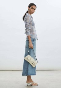 Light blue plaid button-up shirt, medium wash denim skirt, white flip-flops, and a small white handbag with metal accents.