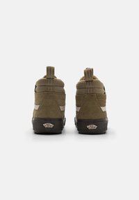 Grønne semskede høje sneakers med en sort gummisål, elastisk sidepanel og en bageste trækstrop. Har et kontrasterende beigestribet design.