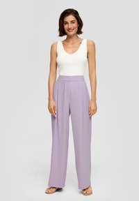 Witte geribbelde tanktop met een diepe V-hals, gecombineerd met hoge, vloeiende lavendelkleurige broek. Glad materiaal, wijde pasvorm.