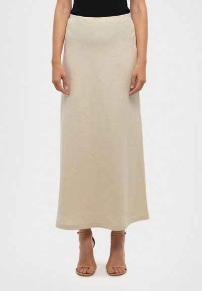 Gonna maxi in lino beige con una texture liscia e una linea dritta. Presenta una vita alta e arriva fino alle caviglie, abbinata a tacchi a strappo color tan.