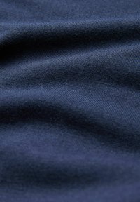Tissu marine avec une texture lisse, présentant de légères ondulations et un motif de tricot uniforme. Aucun logo ou design visible.