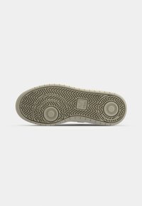 Rubber sneaker outsole in light beige with zigzag pattern and circular accent details. Features a textured surface for traction.