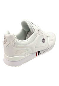 Witte sport sneaker van textuurleer, met een gevlekte zool, gelaagd ontwerp en subtiele rode en marineblauwe accenten. Merken op de zijkant.