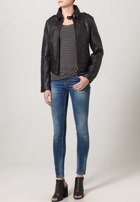 Black leather biker jacket with a zipped front and buttoned collar, paired with a striped top and slim blue jeans. Black heeled sandals.