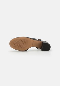 Sorte heler med glatt materiale, åpen tå-design, ankelsnor og en teksturert gummisåle med en naturlig fargebase.