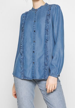 Denim shirt with a button front, long sleeves, ruffled edges along the placket, and a round neckline. Light blue color throughout.