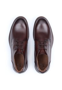 Brune lædersko med glat tekstur, runde tåform og snøredesign. Har syninger rundt om sålen og et diskret logo indvendigt.