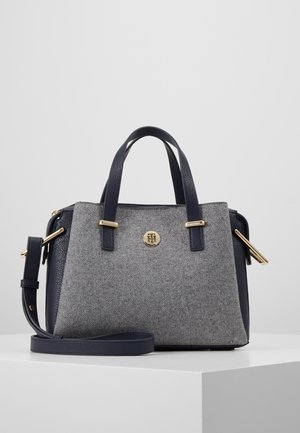 Gray and navy handbag with two handles, adjustable shoulder strap, gold-tone hardware, and a small circular logo on the front.