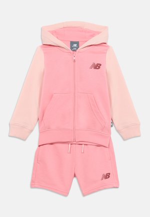 Toddlersæt i to dele fra New Balance i lyserød med hættetrøje med lynlås og matchende shorts, begge med brandlogo.