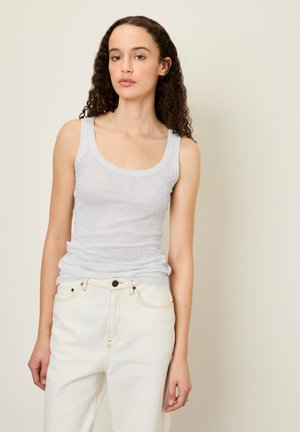 Top in cotone grigio a coste con spalline larghe, caratterizzato da un collo rotondo, abbinato a jeans a vita alta color crema. Design semplice.